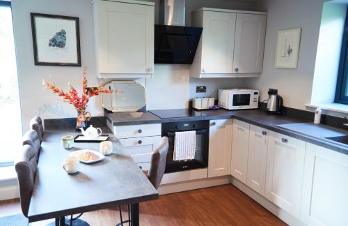 uma cozinha com armários brancos e uma mesa com cadeiras em Cumbria Holiday Apartment Ainstable em Ainstable