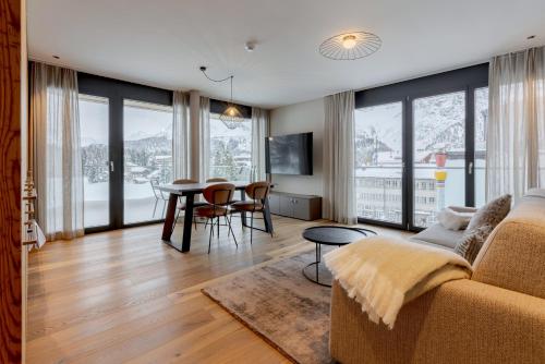 a living room with a couch and a table with chairs at Postresidenz am See in Arosa