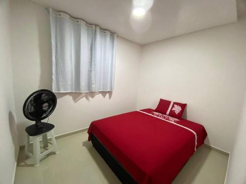 um quarto com uma cama vermelha e uma janela em Apê a 3 min praia de Cotovelo em Parnamirim