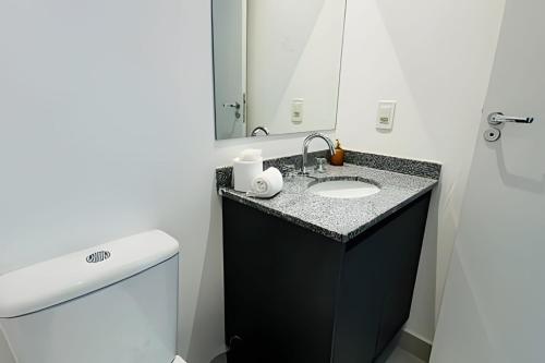 ein Badezimmer mit einem Waschbecken, einem WC und einem Spiegel in der Unterkunft Sampa Sky Particular: Vista Única no Último Andar in São Paulo