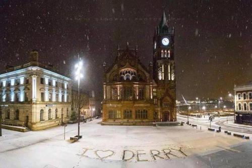a large building with a clock tower in the snow at Helens House Derry City Centre Remarkable 3-Bed in Derry Londonderry