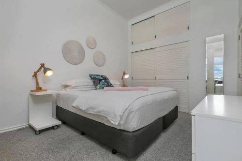 a white bedroom with a bed and a sink at AWSA On the Water Luxury (4003) in Auckland