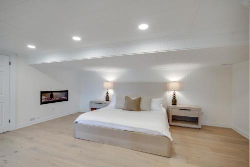a white bedroom with a bed and two night stands at Muskoka Rise in Rosseau