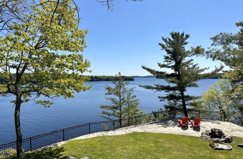 two red chairs sitting on the shore of a lake at Breathtaking view of Lake Rosseau in Rosseau