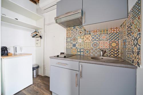 Il dispose d'une cuisine avec un évier et un mur carrelé. dans l'établissement Clery 31, à Paris