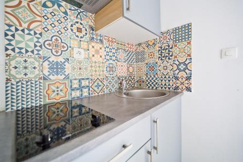 La salle de bains est pourvue d'un lavabo et de carrelage coloré sur le mur. dans l'établissement Clery 31, à Paris