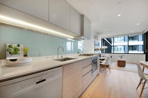 a kitchen with white cabinets and a dining room at Cool and Contemporary on the City Edge in Melbourne