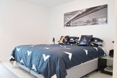 a bedroom with a bed with a blue and white comforter at Luxurious Flemington with Stunning Racecourse View in Melbourne