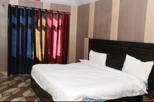 a bedroom with a bed with white sheets and colorful curtains at Rupali home stay in Joshīmath