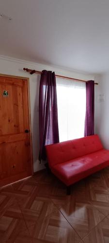 a red couch in a room with a window at Cabañas Tres Islas in Punta de Choros