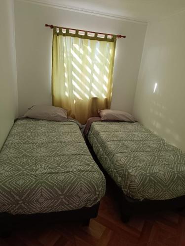 two beds in a small room with a window at Cabañas Tres Islas in Punta de Choros