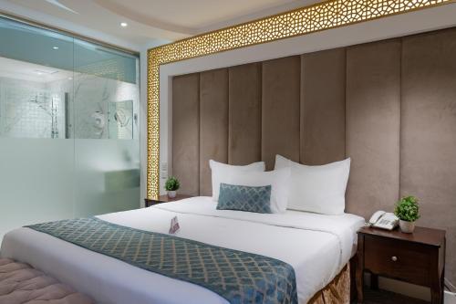 a bedroom with a large white bed and a wall at Holiday Plus Al Salamh- هوليداي بلس السلامه in Jeddah
