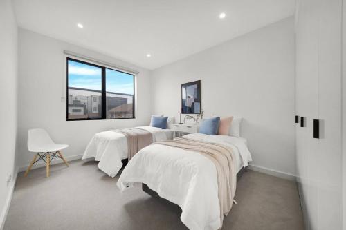 two beds in a white room with a window at Parkside Chic Near Northland in Melbourne