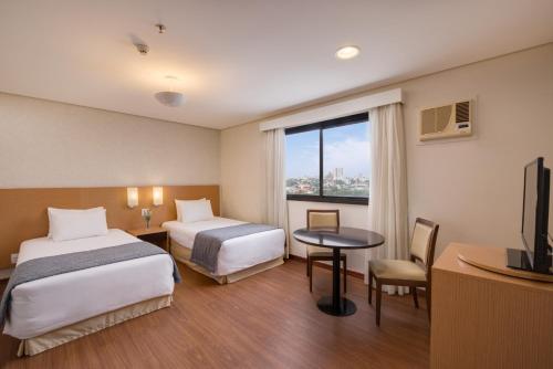 a hotel room with two beds and a table and a television at Blue Tree Premium Londrina in Londrina