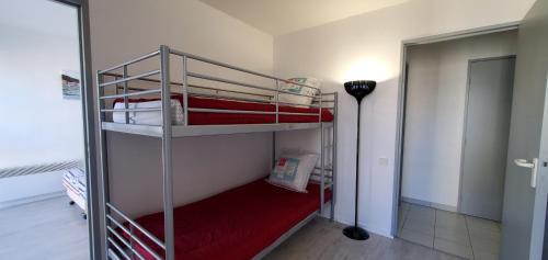 Cette chambre comprend 2 lits superposés dotés de draps rouges. dans l'établissement CESAREE BORGHESE, Port Frejus, Grand 2-3 pieces, 4, à Fréjus