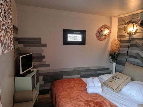 a hotel room with a bed and a television at L Atypic, chalet bien être aux portes de Vannes in Monterblanc
