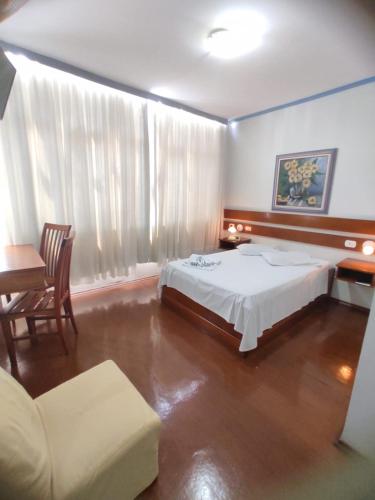 a bedroom with a bed and a couch and a table at HOTEL MARAMBAIA in Guaxupé