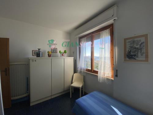 ein Schlafzimmer mit einem Bett, einem Fenster und einem Stuhl in der Unterkunft CONCHIGLIA in San Vincenzo