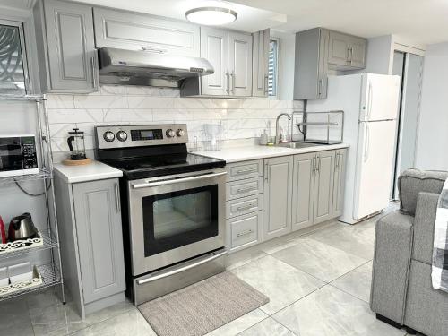 a kitchen with stainless steel appliances and white cabinets at Cozy & Comfortable basement apartment in Mississauga