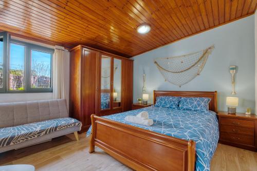 a bedroom with a bed and a couch and a window at Ocean Blue & Nature Townhouse - Bikes included in Ericeira