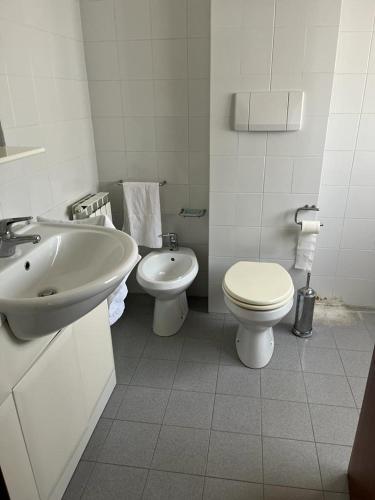 a white bathroom with a sink and a toilet at Grande e luminoso appartamento in Lido di Classe