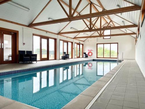 a large swimming pool in a building with windows at The Gallery, Blythburgh in Blythburgh