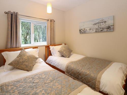 een slaapkamer met 2 bedden en een raam bij The Lodge at Orchard House in Norwich