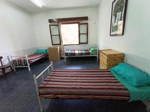 聖薩爾瓦多德胡胡伊的住宿－HOSTEL LA ESPAÑOLA，客房设有两张床、一张沙发和一个窗口。