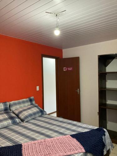 a bedroom with a bed and a red wall at Recanto das Pedras Floripa in Florianópolis