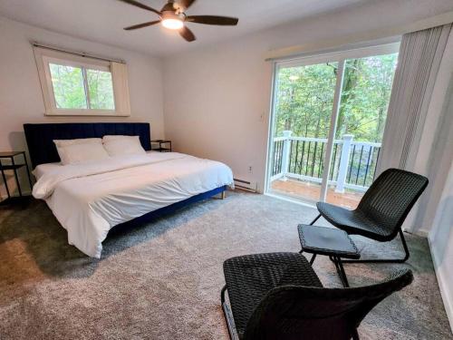 1 dormitorio con 1 cama, 2 sillas y ventana en Lovely Poconos getaway, en Tobyhanna