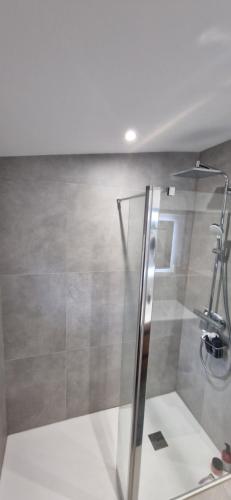 a shower with a glass door in a bathroom at Le jusqu'à 7 in Le Cendre