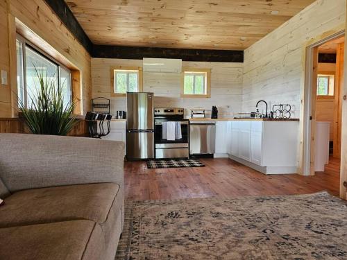 a living room with a couch and a kitchen at Horse Farm Retreat in Sherburne