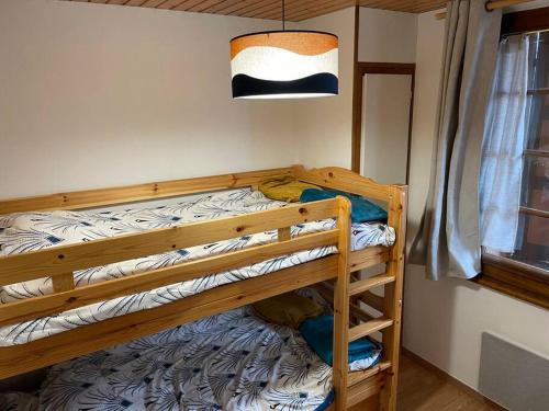 drewnianym łóżkiem piętrowym w pokoju z oknem w obiekcie Appartement Cosy idéalement situé w mieście Le Grand-Bornand