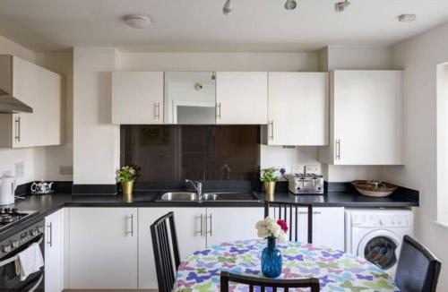 a kitchen with white cabinets and a table with a vase on it at 2 mins away from Hammersmith St. in London