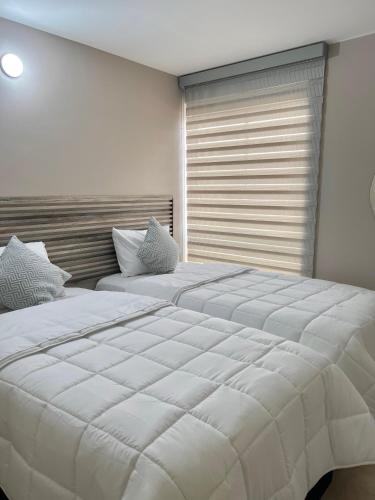 ein Schlafzimmer mit zwei Betten und einem Fenster in der Unterkunft Lindo y cómodo apartamento 804 in Cali