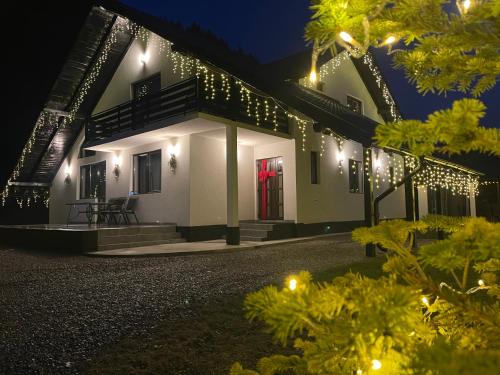 a house lit up at night with christmas lights at Casa cu Tihna in Fundu Moldovei