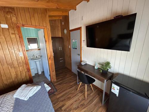 Habitación con escritorio y TV en la pared. en Hostal Senderos del Sur, en Freire