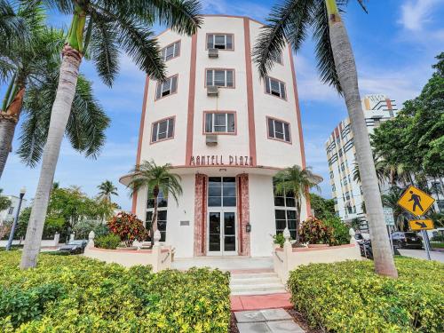 a pink building with palm trees in front of it at Mantell Plaza Apartments in Miami Beach