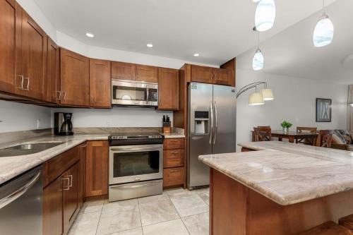 a kitchen with wooden cabinets and stainless steel appliances at NEW Luxury Condo at Kameole Beach in Wailea