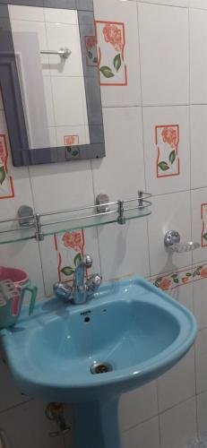 La salle de bains est pourvue d'un lavabo bleu et d'un miroir. dans l'établissement ShivaPuri Homestay, à Darjeeling