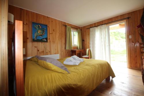 a bedroom with a yellow bed and a window at Hotel Lodge Fundo Laguna Blanca in Curacautín