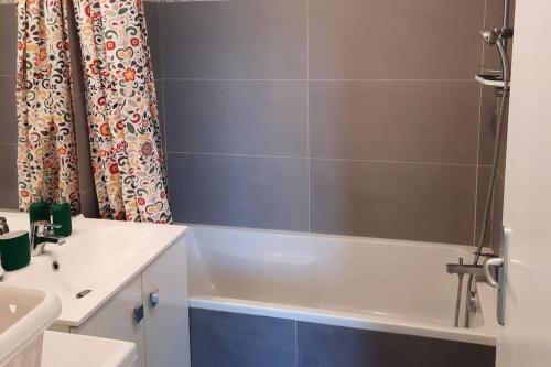 a bathroom with a white sink and a bath tub at Magnifique appartement avec terrasse et parking, 8 Personnes in Nanterre