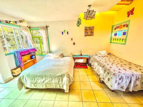 1 dormitorio con 2 camas y mesa. en Casa Ecológica, en Tepoztlán