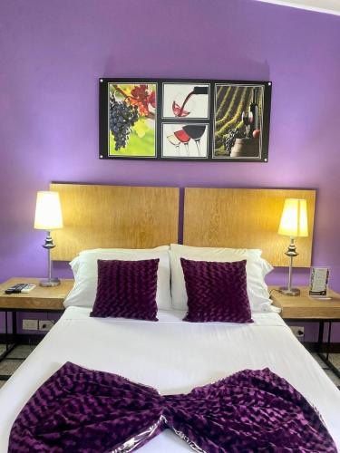 a bedroom with a large bed with purple walls at Hotel Aromax del Campestre in Medellín