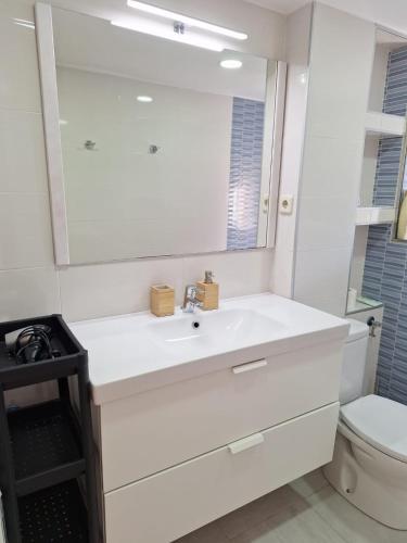 Baño blanco con lavabo y espejo en Apartamento cercano a IFEMA, Aeropuerto, Clinica Universitaria Navarra y Civitas Metropolitano en Madrid