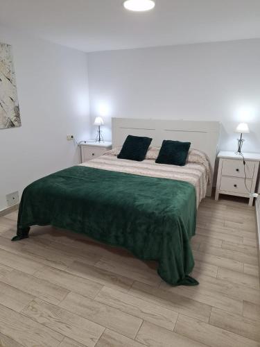 ein Schlafzimmer mit einem großen Bett und einer grünen Decke in der Unterkunft Apartamento cercano a IFEMA, Aeropuerto, Clinica Universitaria Navarra y Civitas Metropolitano in Madrid