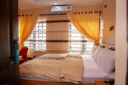 1 dormitorio con 1 cama y una ventana con cortinas amarillas en Dopad Hills Hotel and Suites en Ojo