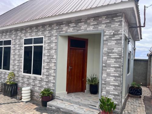 een bakstenen huis met een bruine deur en potplanten bij Dodoma Home Apartments in Dodoma