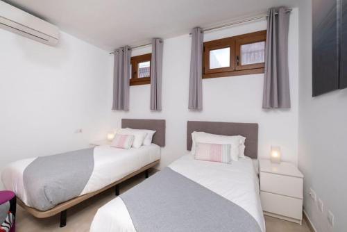 twee bedden in een kamer met witte muren en ramen bij Casa Familia in Playa Blanca