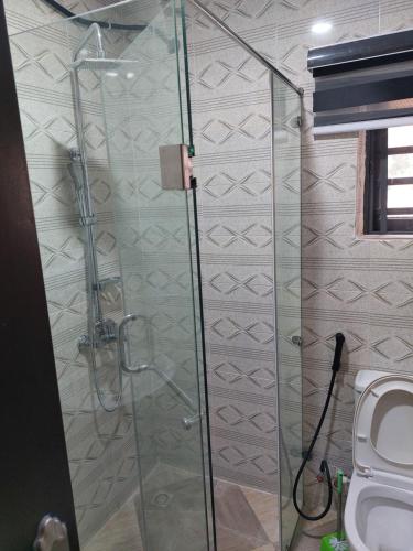 uma casa de banho com uma cabina de duche em vidro e um WC. em Dopad Hills Hotel and Suites em Ojo